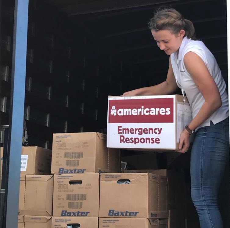 Woman unloading boxes of medical supply from a truck