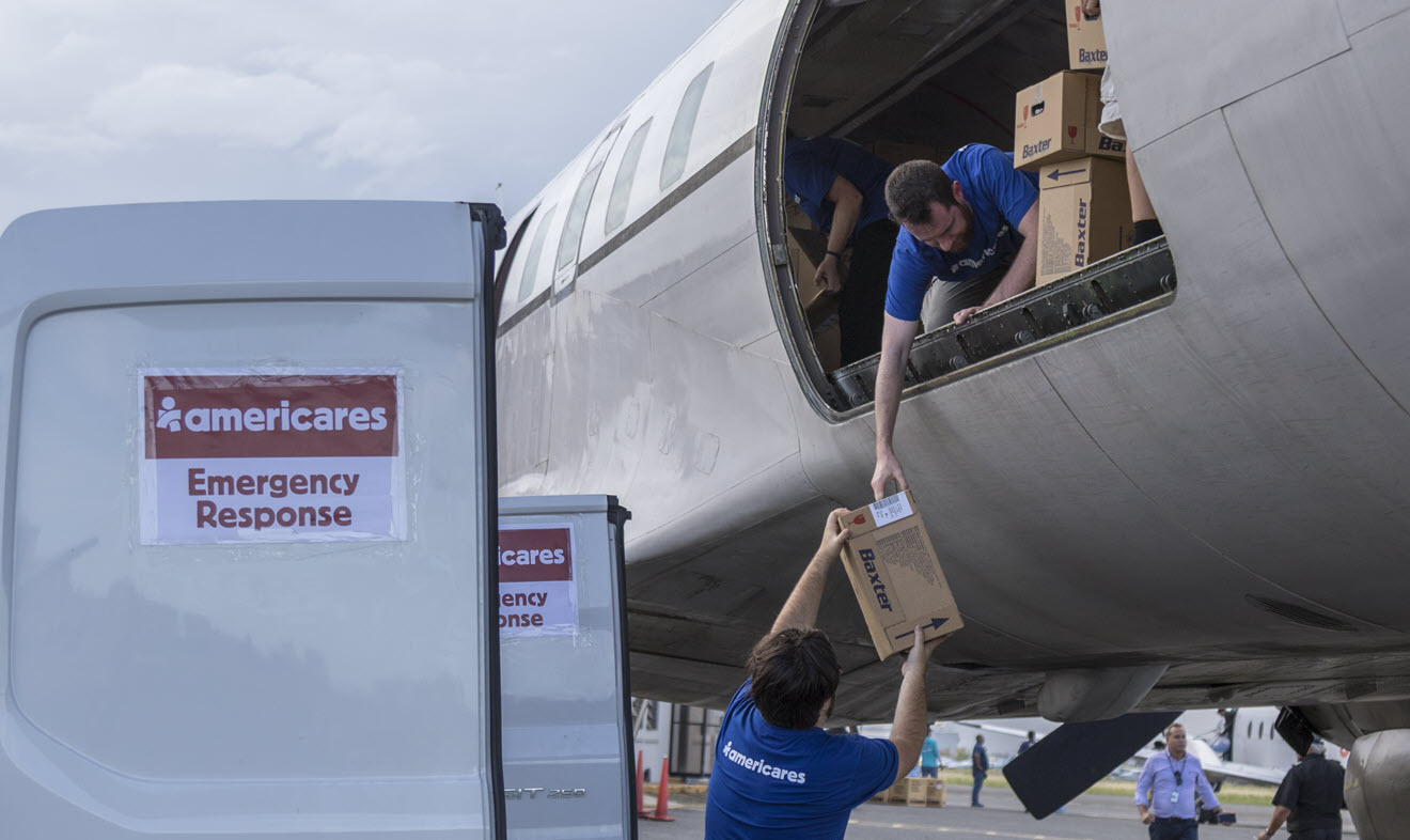 Image of volunteers unloading boxes of medical supplies from cargo plane